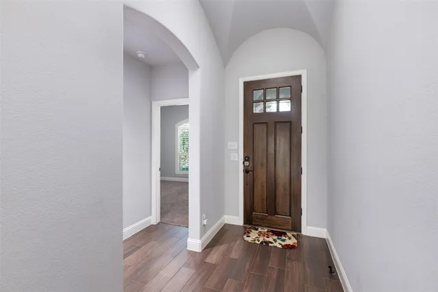a view of a hallway with wooden floor and a mirror