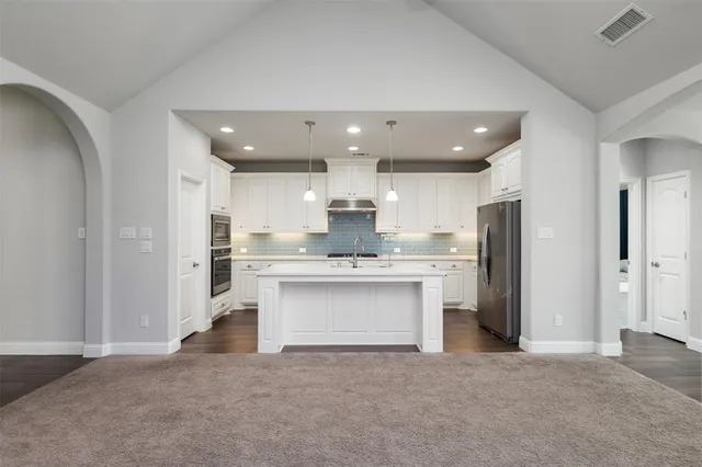 a view of kitchen with stainless steel appliances granite countertop cabinets and chandelier