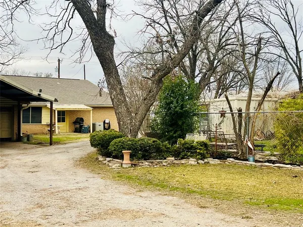 a front view of a house with a dirt yard and a large tree