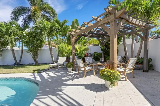 a view of a backyard with lawn chairs under a large tree