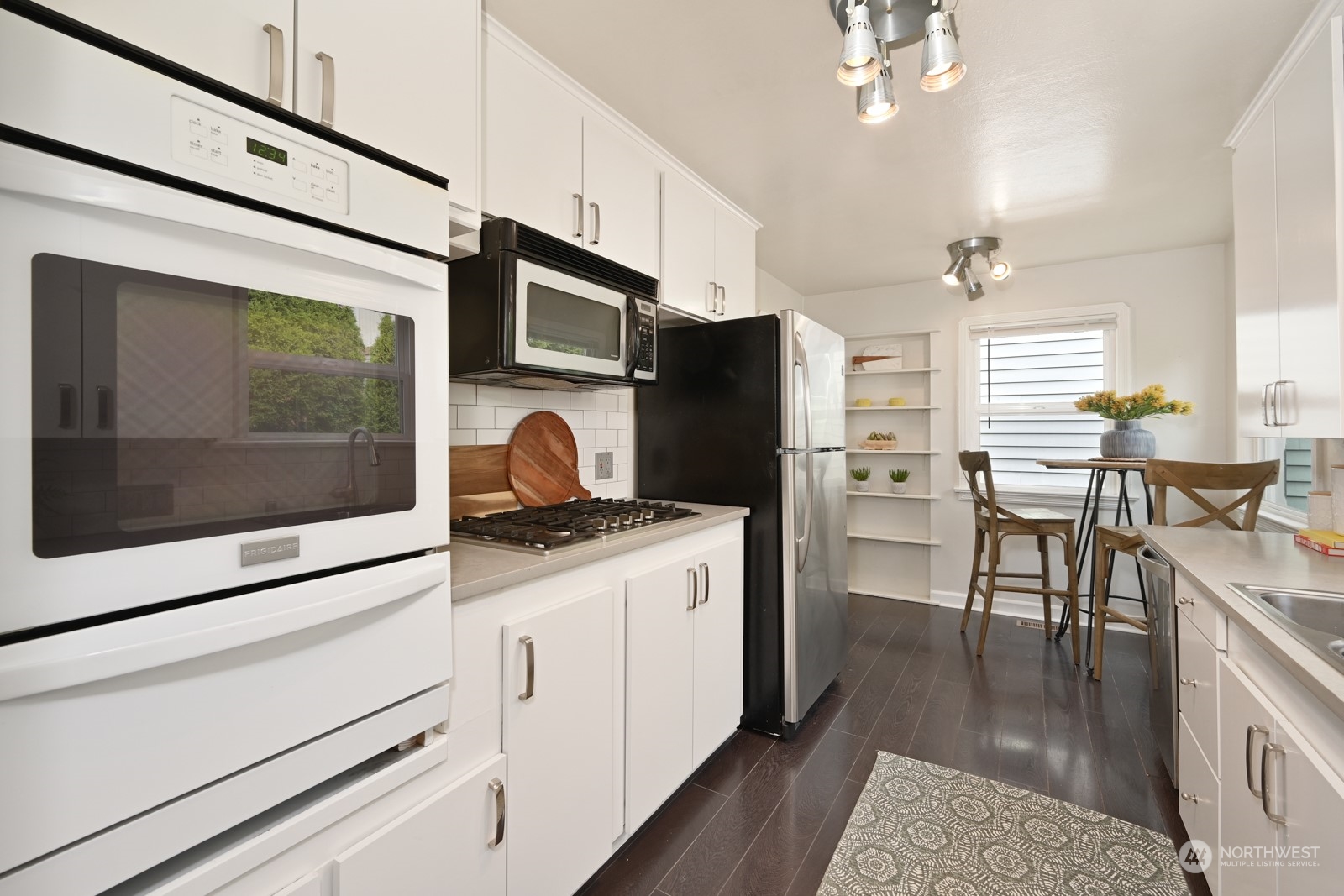 6037 Fauntleroy Way Southwest Seattle, WA 98136 - Photo 9 of 37 a kitchen with stainless steel appliances kitchen island granite countertop a stove top oven a refrigerator a dining table and chairs with wooden floor