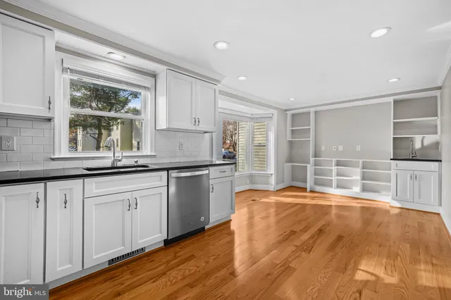 a kitchen with granite countertop a oven a sink dishwasher and cabinets with wooden floor