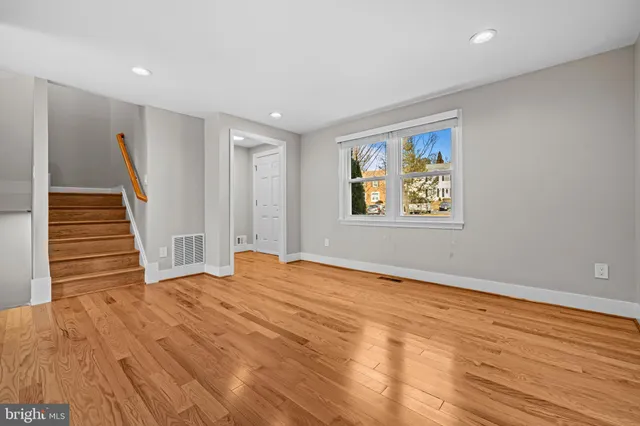 a view of an empty room with wooden floor and stairs