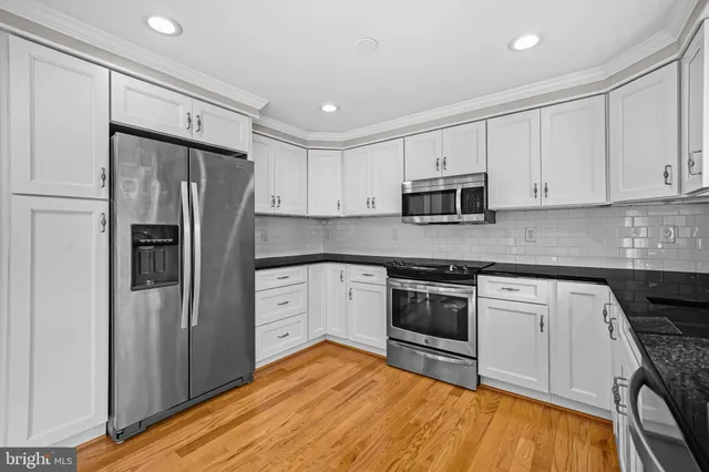 a kitchen with granite countertop a refrigerator stove and microwave