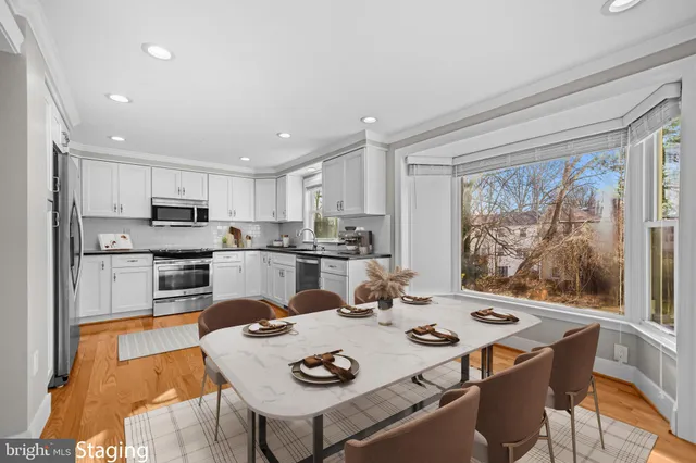 a open dining room with stainless steel appliances a table and chairs