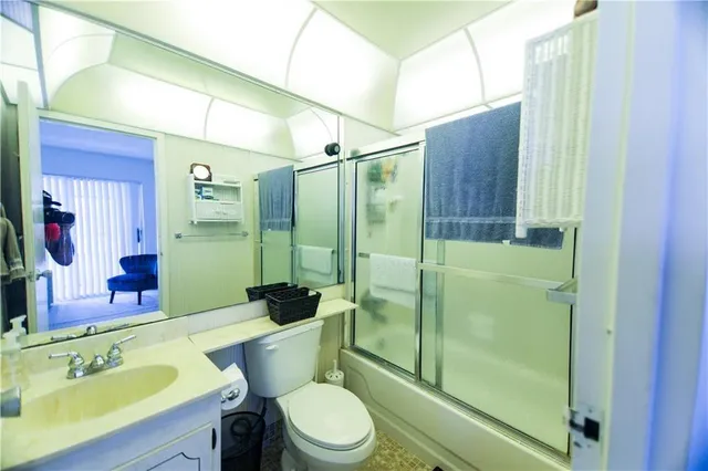 a bathroom with a shower sink vanity mirror and toilet