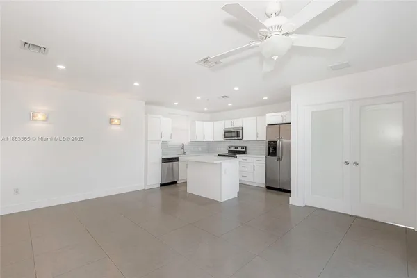 a large kitchen with white cabinets and stainless steel appliances