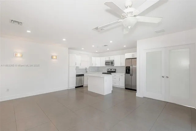 a large kitchen with white cabinets and stainless steel appliances