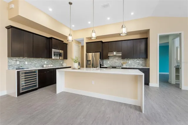 a large kitchen with stainless steel appliances a large counter top a sink a window and wooden floor
