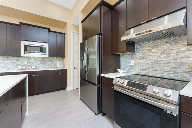a large kitchen with a large counter top stainless steel appliances and wooden floor