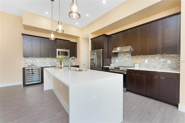 a large kitchen with stainless steel appliances kitchen island granite countertop a sink counter space cabinets and a large window