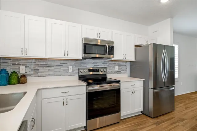 a kitchen with cabinets stainless steel appliances and wooden floor