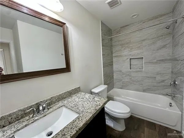 a bathroom with a granite countertop sink mirror vanity and toilet