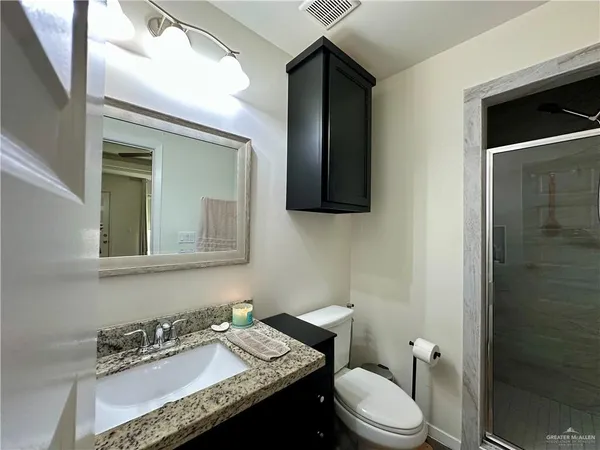 a bathroom with a granite countertop sink vanity mirror and toilet