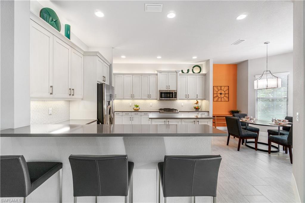 4427 Caldera Circle Naples, FL 34119 - Photo 15 of 50 a kitchen with kitchen island granite countertop wooden cabinets and counter space
