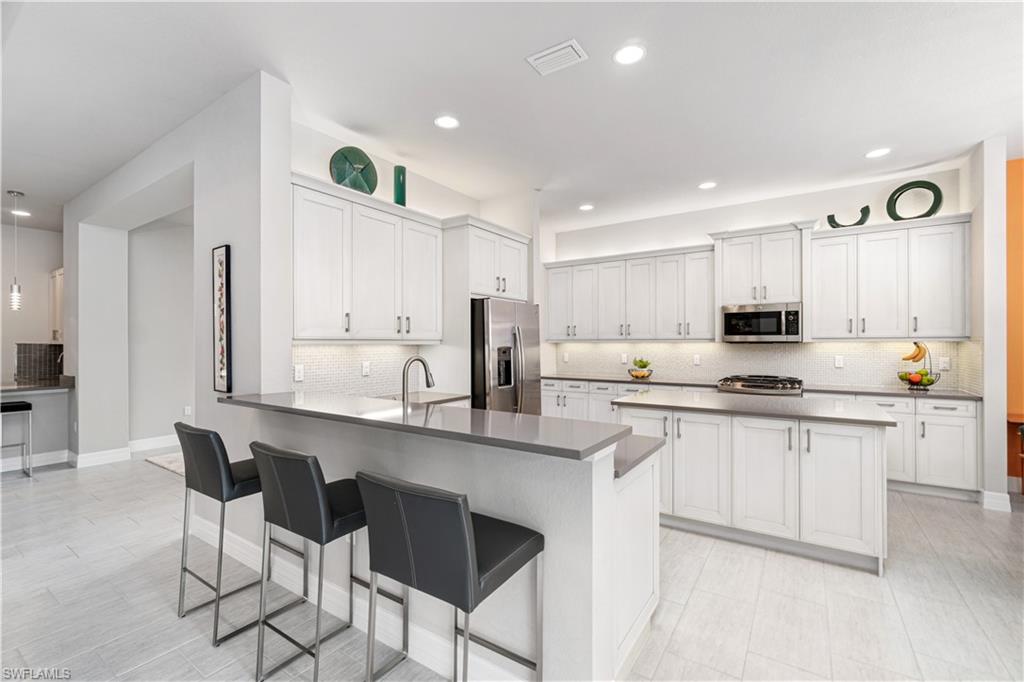 4427 Caldera Circle Naples, FL 34119 - Photo 21 of 50 a kitchen with stainless steel appliances granite countertop a white cabinets and a stove top oven