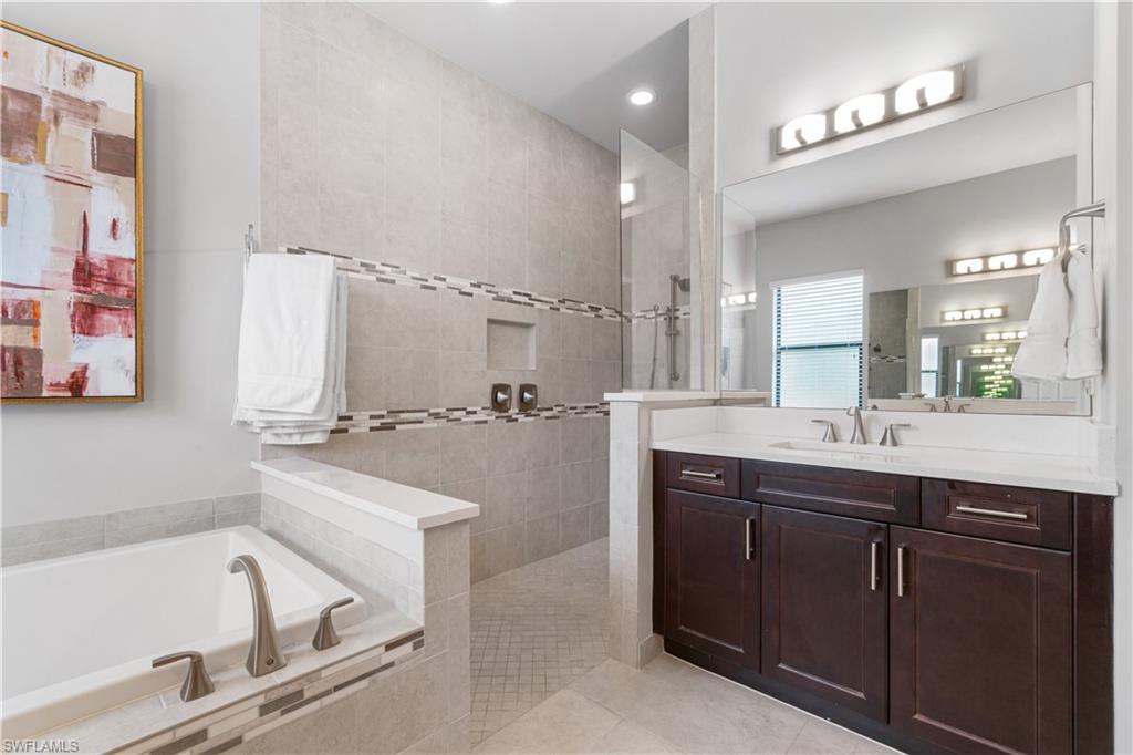 4427 Caldera Circle Naples, FL 34119 - Photo 40 of 50 a bathroom with a bathtub a double vanity sink and mirror