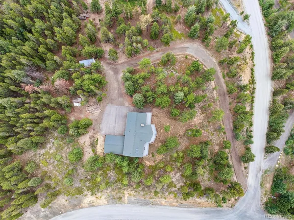 an aerial view of residential house with outdoor space and trees all around