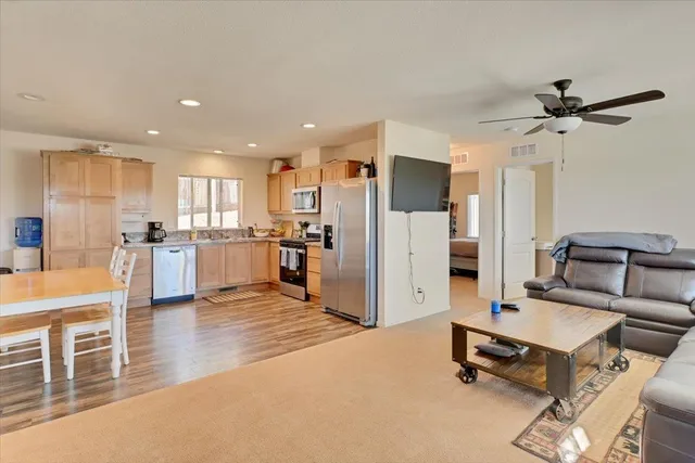 a living room with stainless steel appliances furniture refrigerator and kitchen view