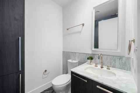 a bathroom with a granite countertop sink toilet and mirror