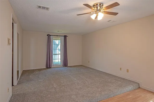 a view of a big room with windows and chandelier fan
