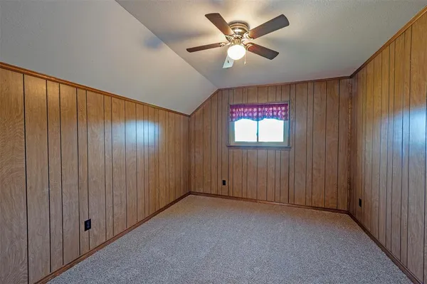 an empty room with windows and a chandelier fan
