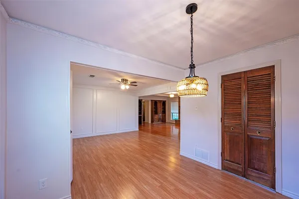 a dining room with wooden floor chandelier and kitchen view