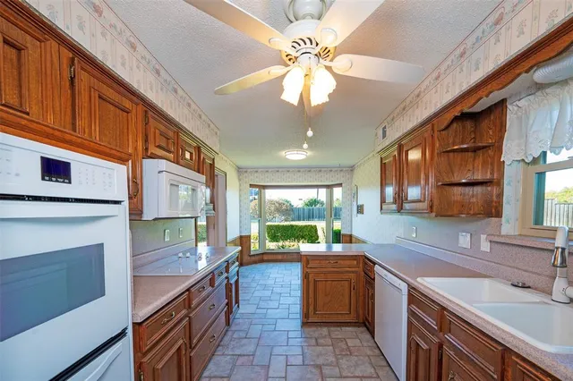 a kitchen with stainless steel appliances granite countertop a sink a stove cabinets counter space and a window