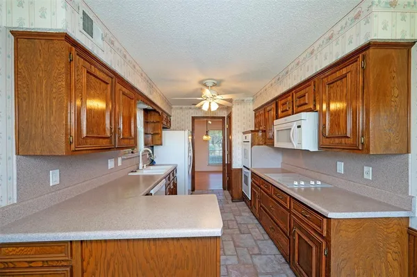 a large kitchen with stainless steel appliances granite countertop a sink dishwasher stove and wooden cabinets
