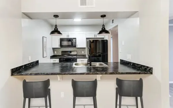 a kitchen with stainless steel appliances granite countertop a sink a microwave refrigerator and chairs
