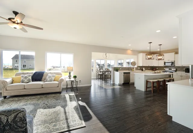 a living room with couches and kitchen view with wooden floor