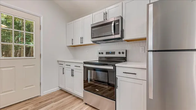 an empty room with wooden floor cabinet and windows