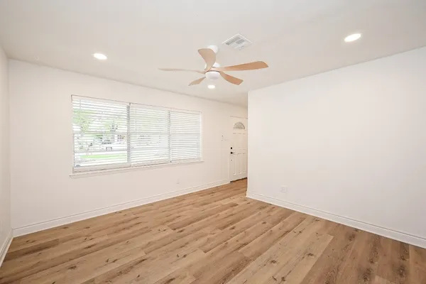 an empty room with wooden floor ceiling fan and windows
