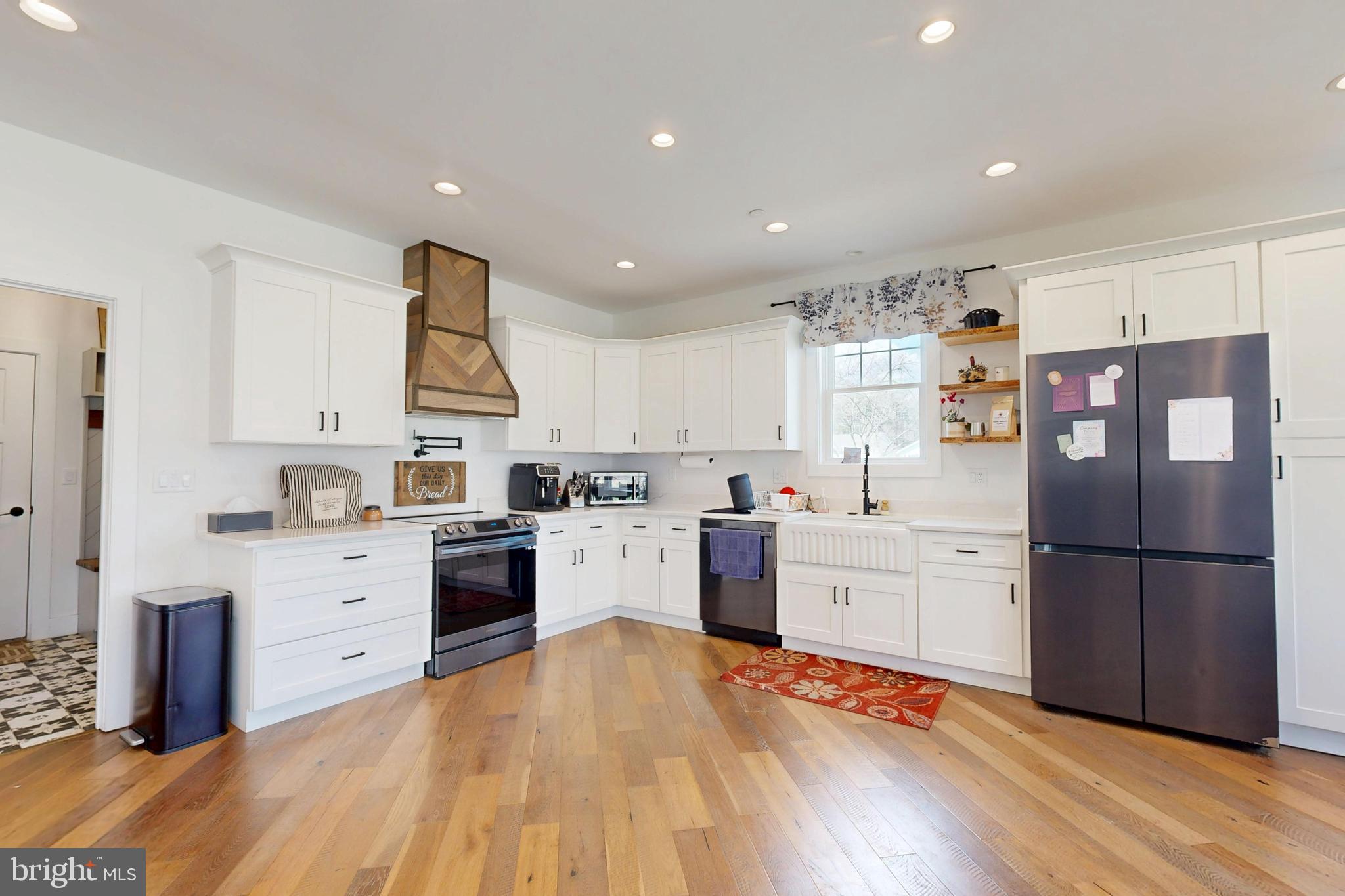 23730 Henry Road Ridgely, MD 21660 - Photo 8 of 28 a large kitchen with stainless steel appliances granite countertop a refrigerator a stove and white cabinets with wooden floor
