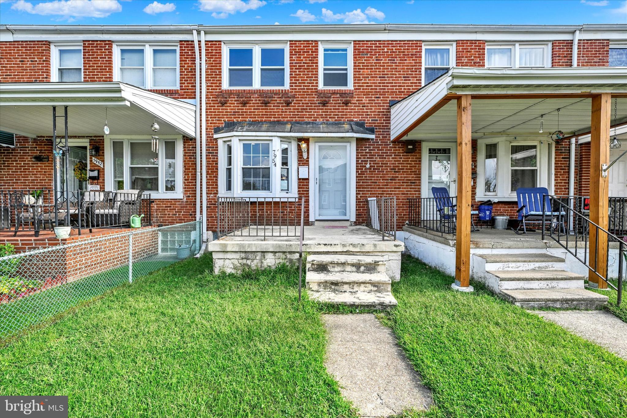 front view of a brick house with a yard and table and chairs next to a yard