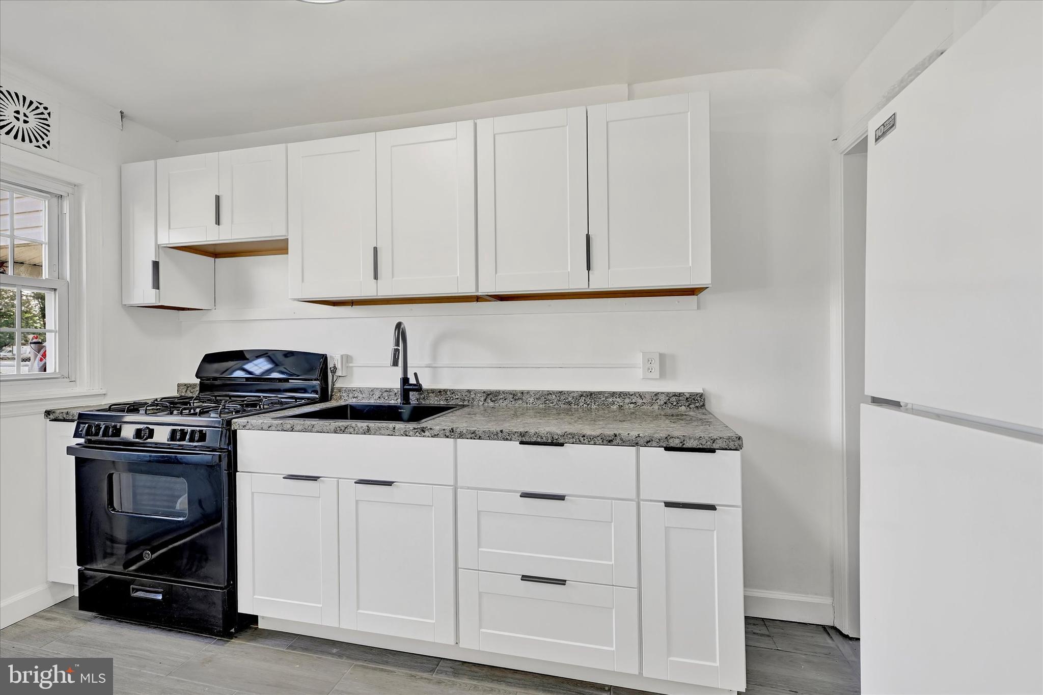 7954 Kavanagh Road Baltimore, MD 21222 - Photo 9 of 16 a kitchen with granite countertop a stove sink and cabinets
