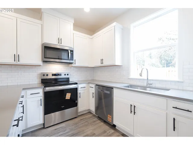 a kitchen with stainless steel appliances granite countertop a sink a stove a microwave and wooden cabinets