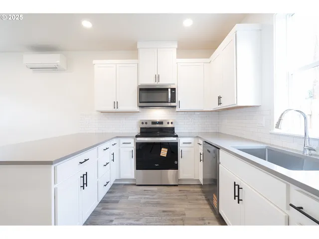 a kitchen with granite countertop white cabinets and black stainless steel appliances