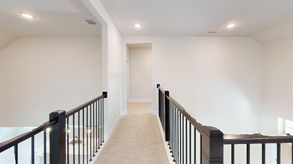 2708 Andesite Road McKinney, TX 75071 - Photo 15 of 35 Carpeted hallway featuring a dark wood handrail with black iron balusters, recessed lighting, and white baseboards