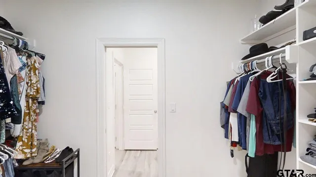 a view of walk in closet with clothes and shoes