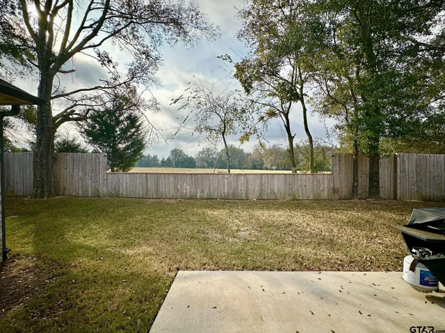 a view of a yard with a large tree and wooden fence