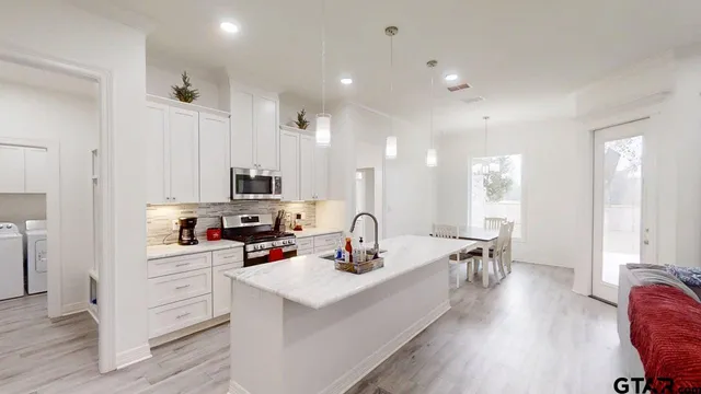 a kitchen with kitchen island granite countertop a sink cabinets and wooden floor
