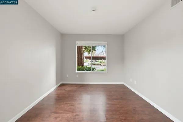 an empty room with wooden floor and windows