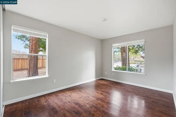 a view of an empty room with wooden floor and a window