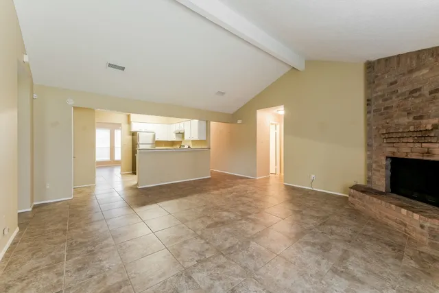 a view of an empty room with a fireplace and a window
