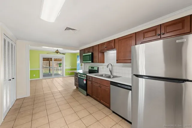 a large kitchen with a stove a sink dishwasher and a refrigerator with wooden floor
