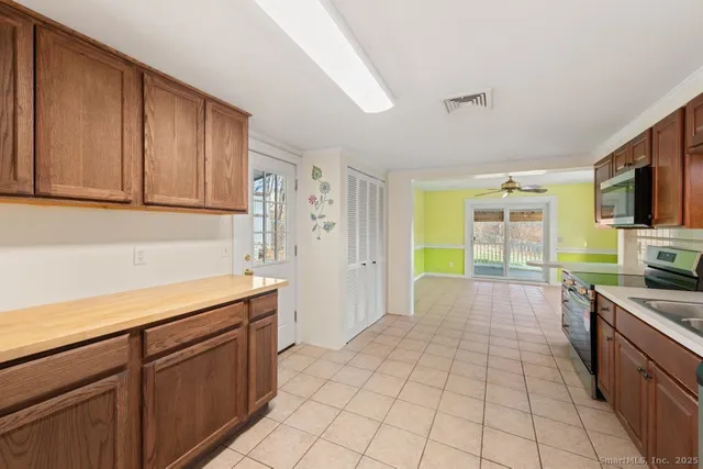 a large kitchen with granite countertop a stove top oven microwave and cabinets