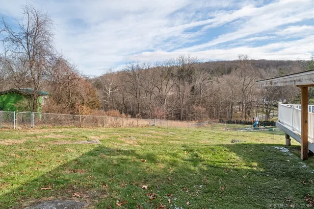 a small white house with a large pool next to a yard