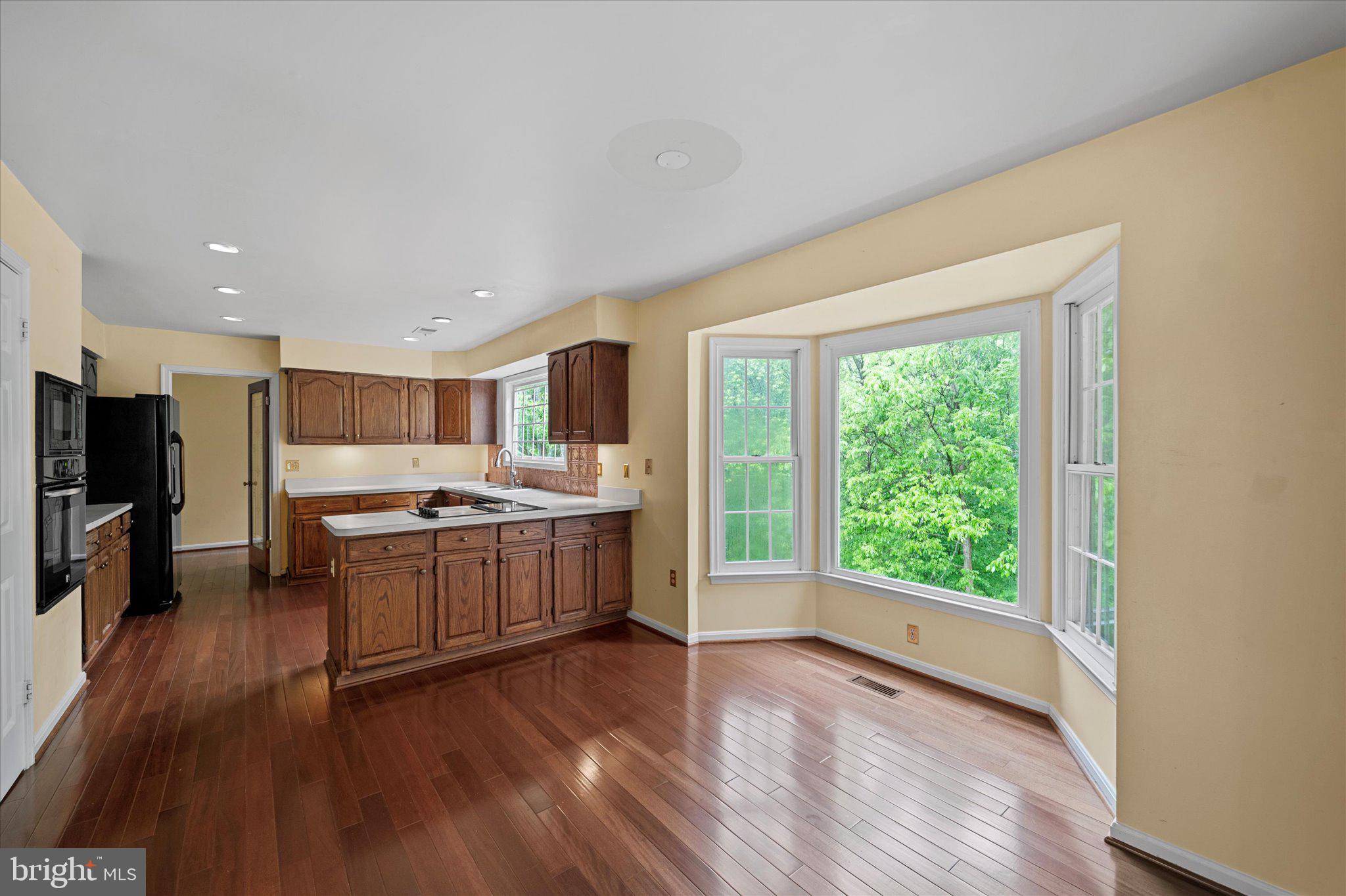6832 Compton Heights Circle Clifton, VA 20124 - Photo 16 of 54 a large kitchen with stainless steel appliances granite countertop a stove a sink a refrigerator and white cabinets with wooden floor