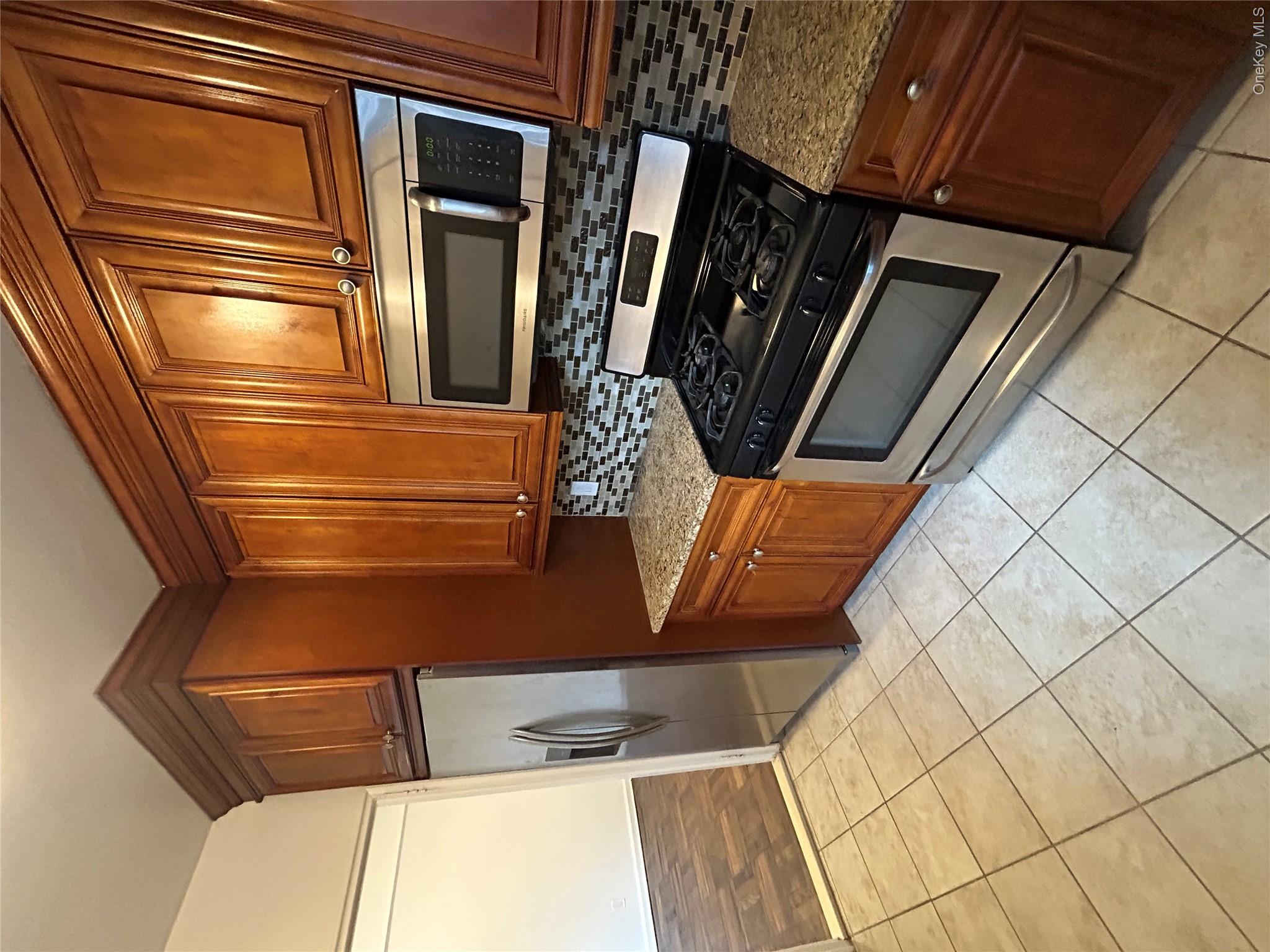 230 Pelham Road, Unit 2E New Rochelle, NY 10805 - Photo 1 of 1 a kitchen with granite countertop a refrigerator stove and microwave